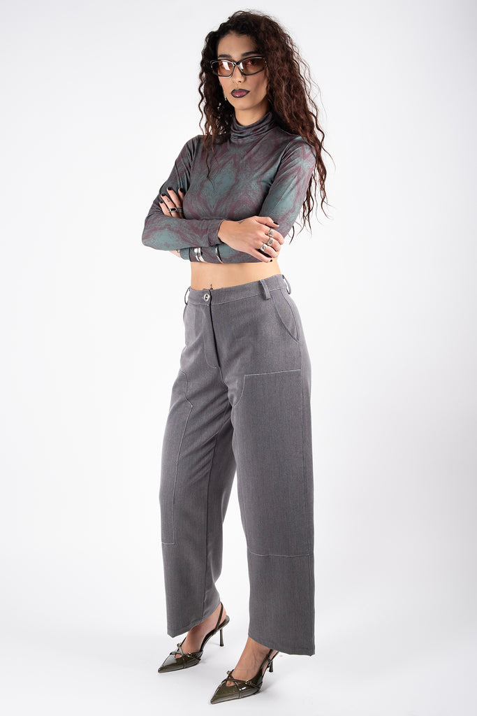 Woman wearing a patterned top and gray pants on a white background